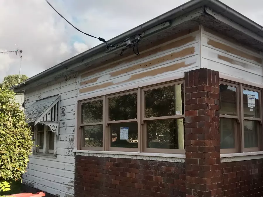 Weathered front corner of timber house before exterior painting