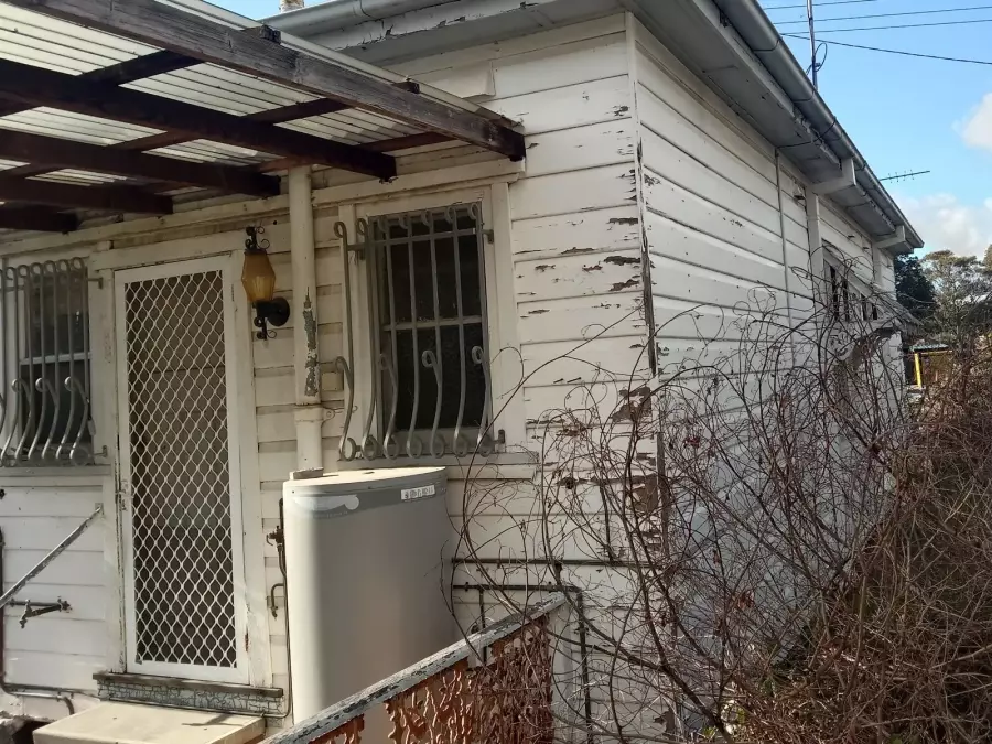 Weathered side and rear of timber house before restoration